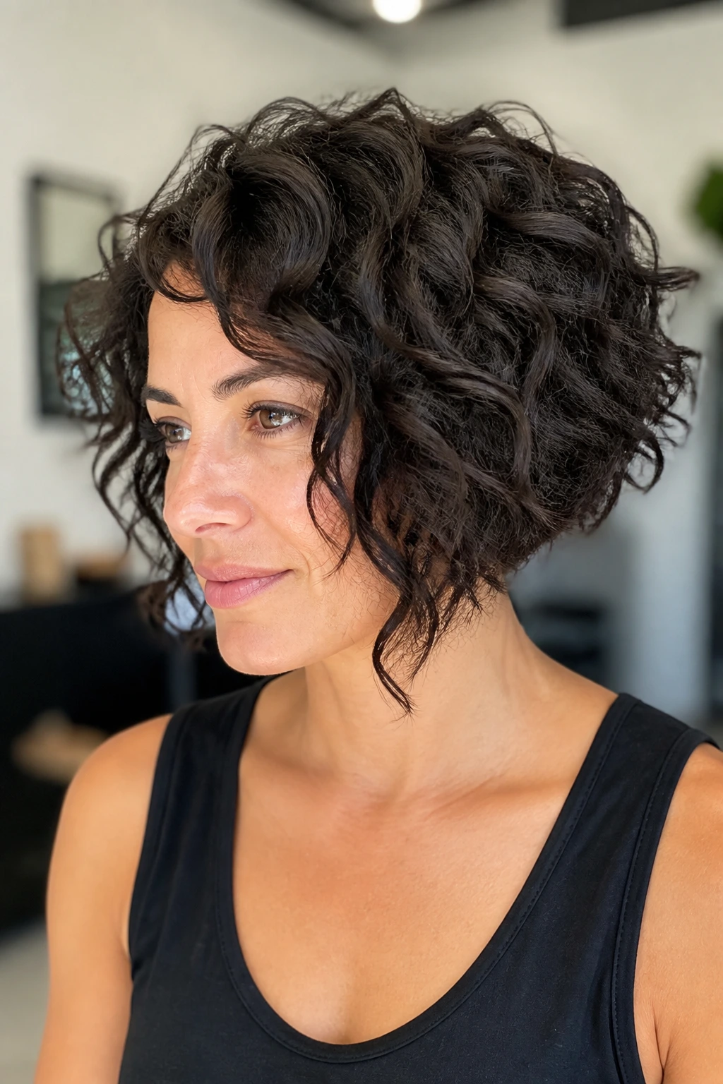 Portrait of a real woman with angled curly bob and forward-leaning shape