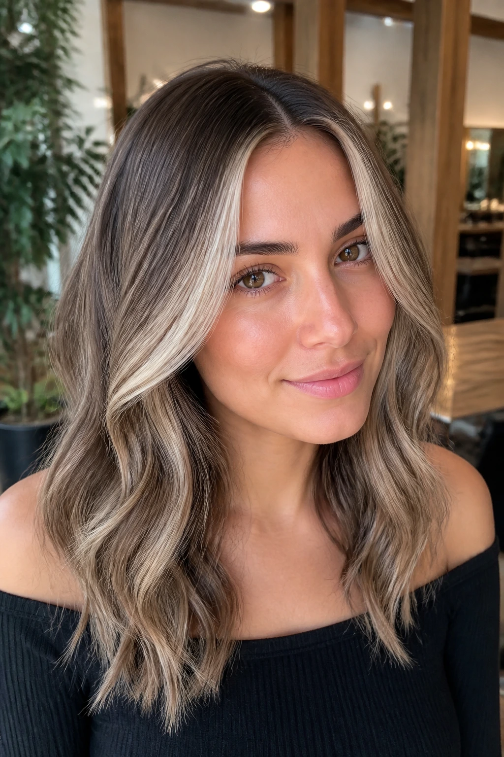 Close-up of a real woman with an ashy beige money piece and cool-toned balayage in a modern salon.