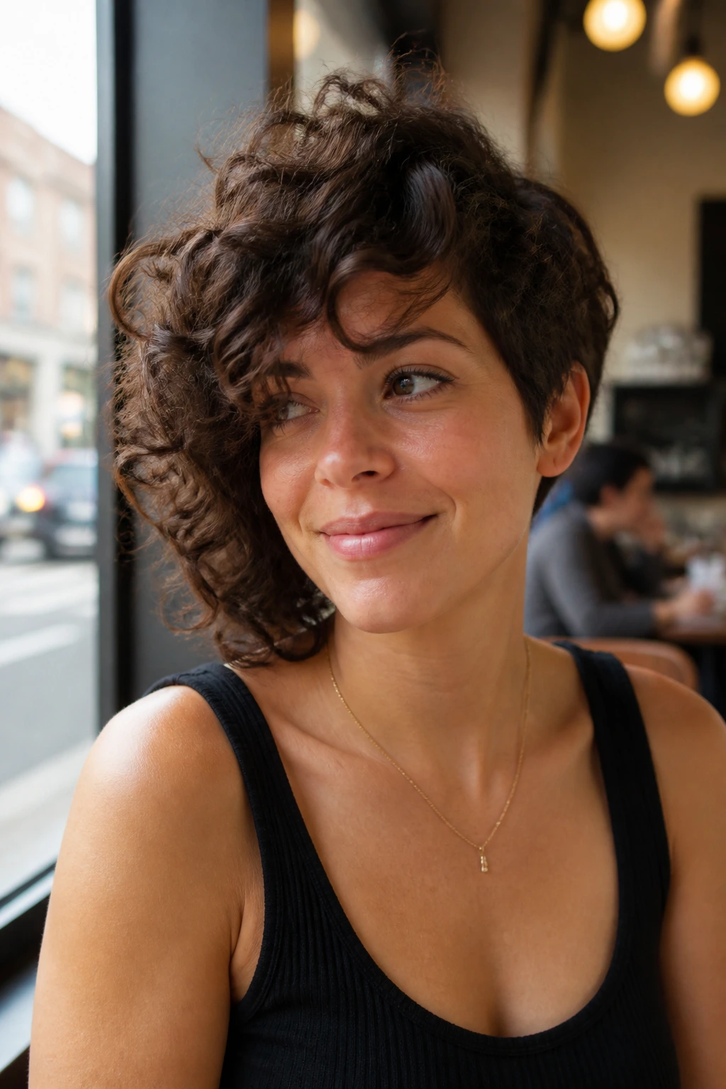 Close-up of a real woman with an asymmetrical curly haircut showing a subtle length difference
