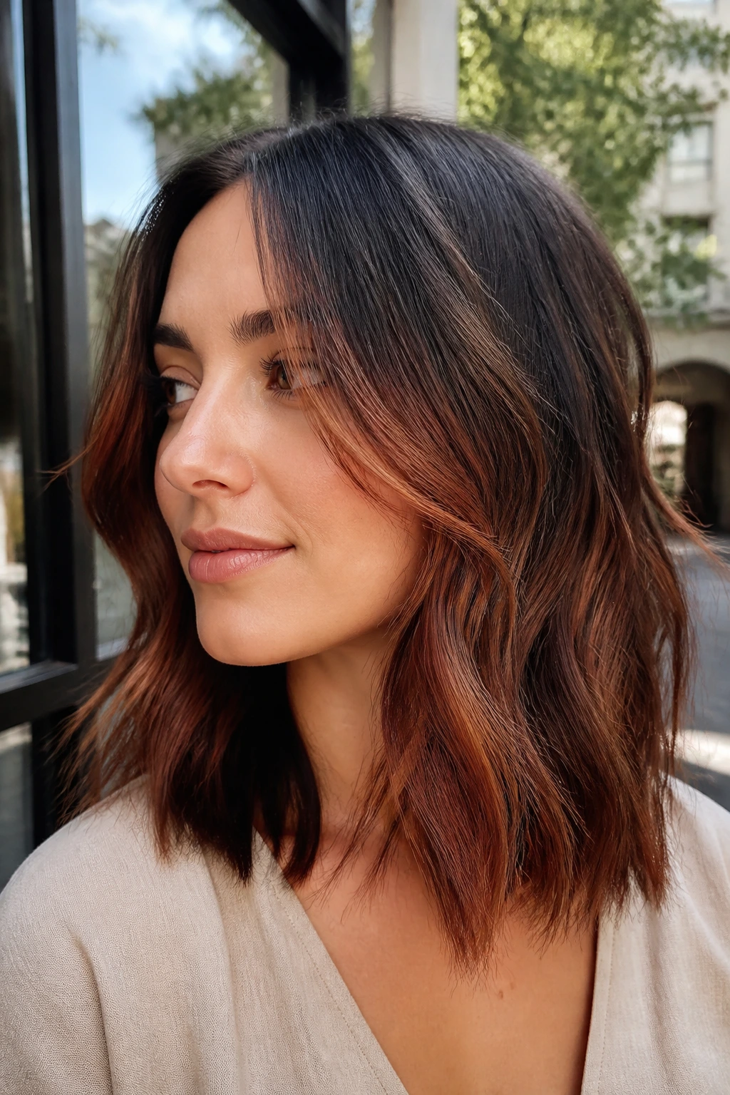 Close-up of auburn balayage on dark brown shoulder-length hair with subtle face-framing pieces