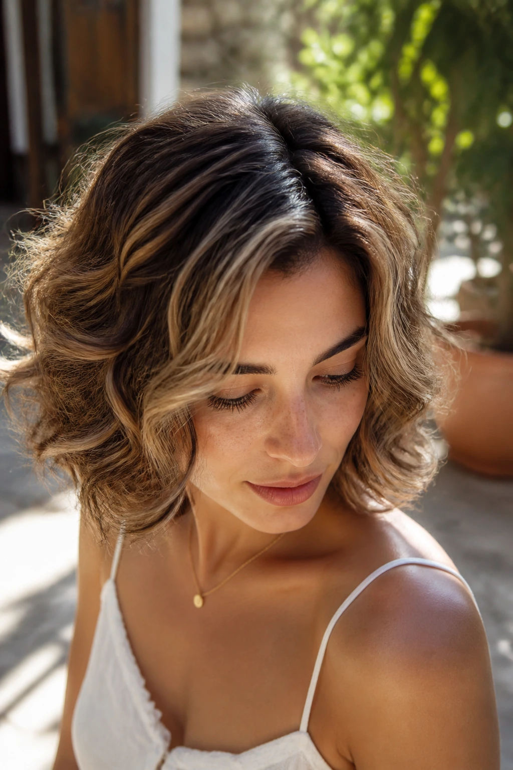 Portrait of a woman with sun-lit balayage bob and light ribbons around the face.
