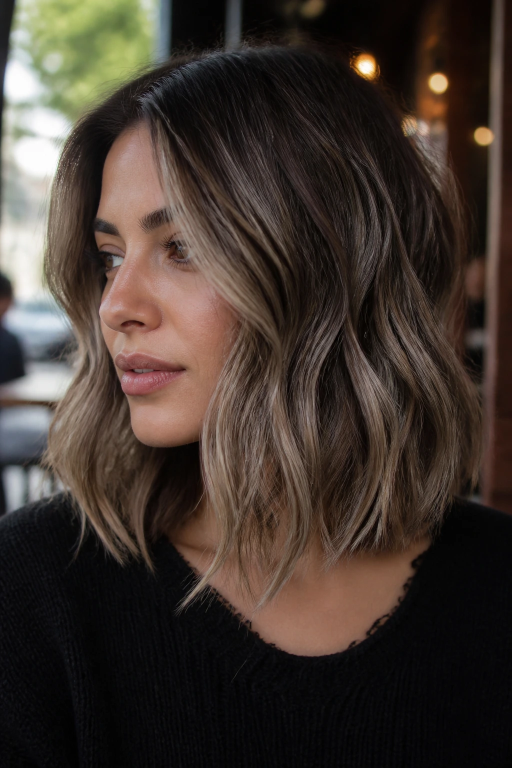 Close-up of mushroom brown balayage on a wavy lob in daylight
