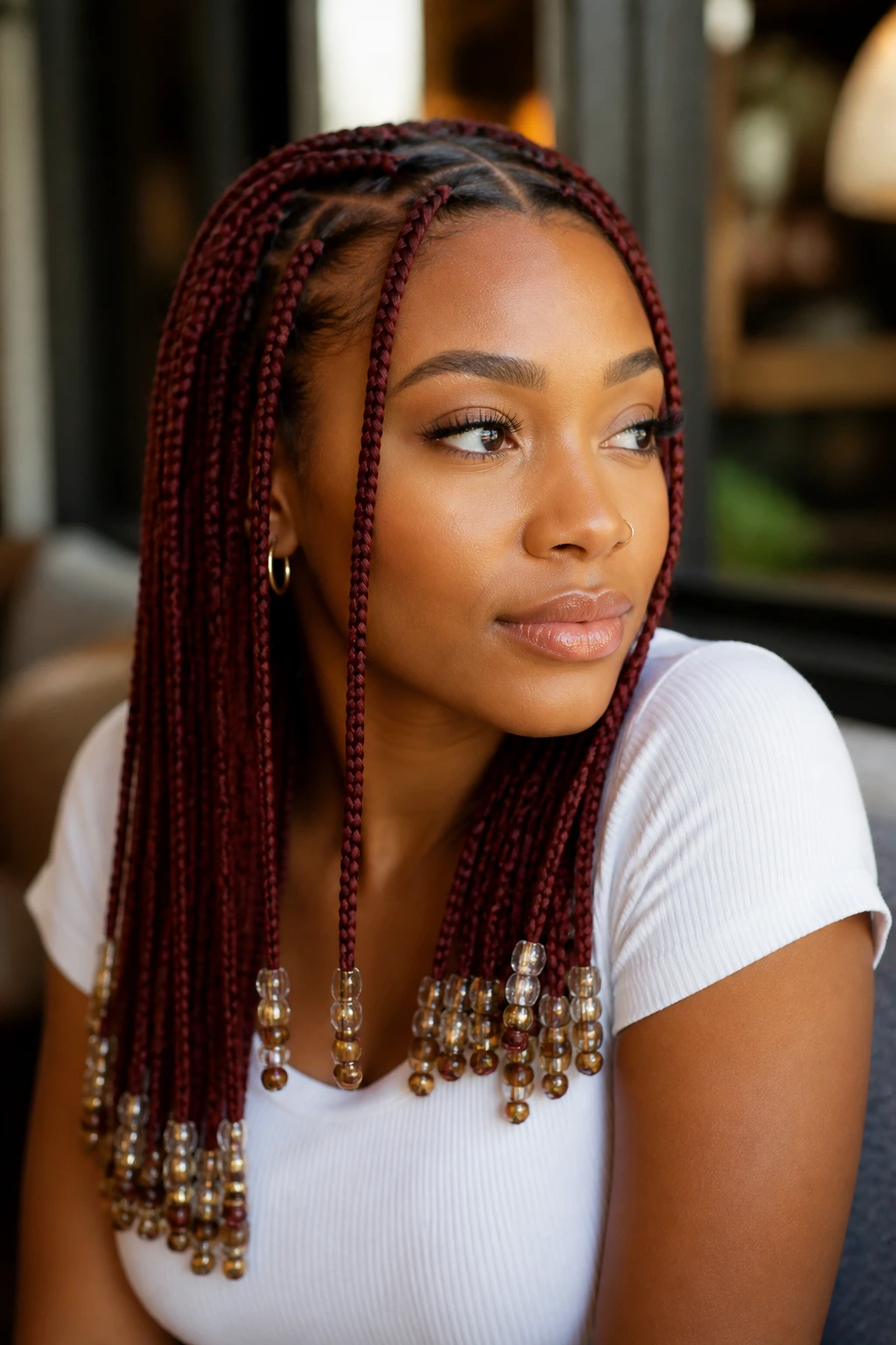 Close-up of burgundy knotless braids with beads on a real person