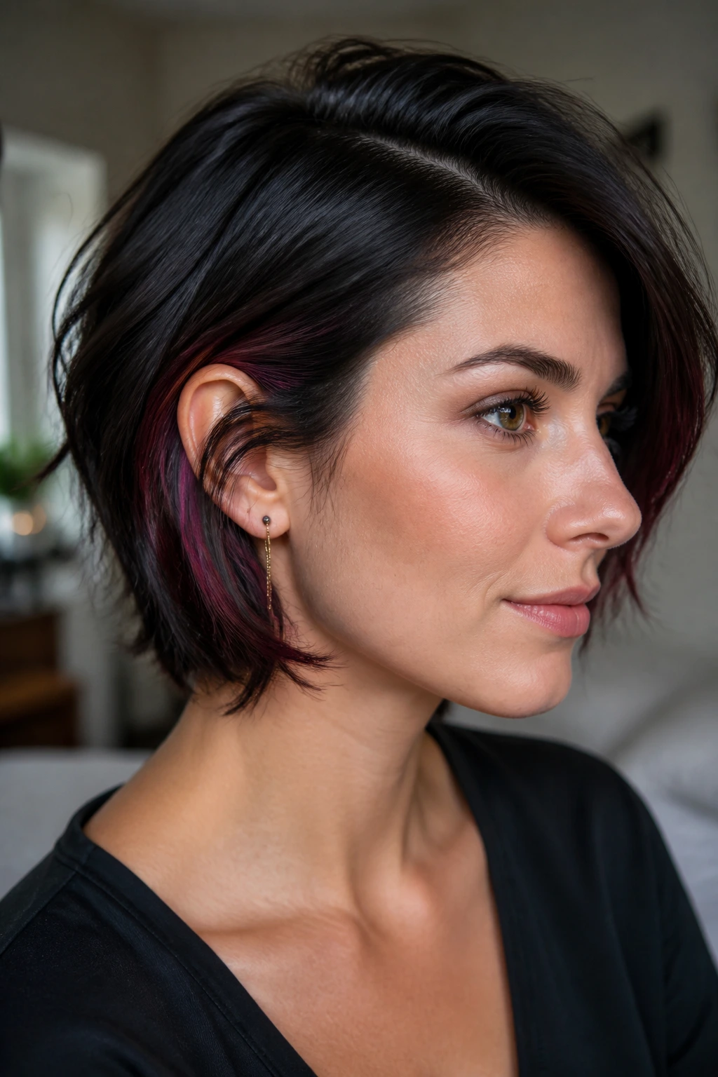 Close-up of a real woman with short dark hair showing berry-toned peekaboo highlights tucked under the top layer.