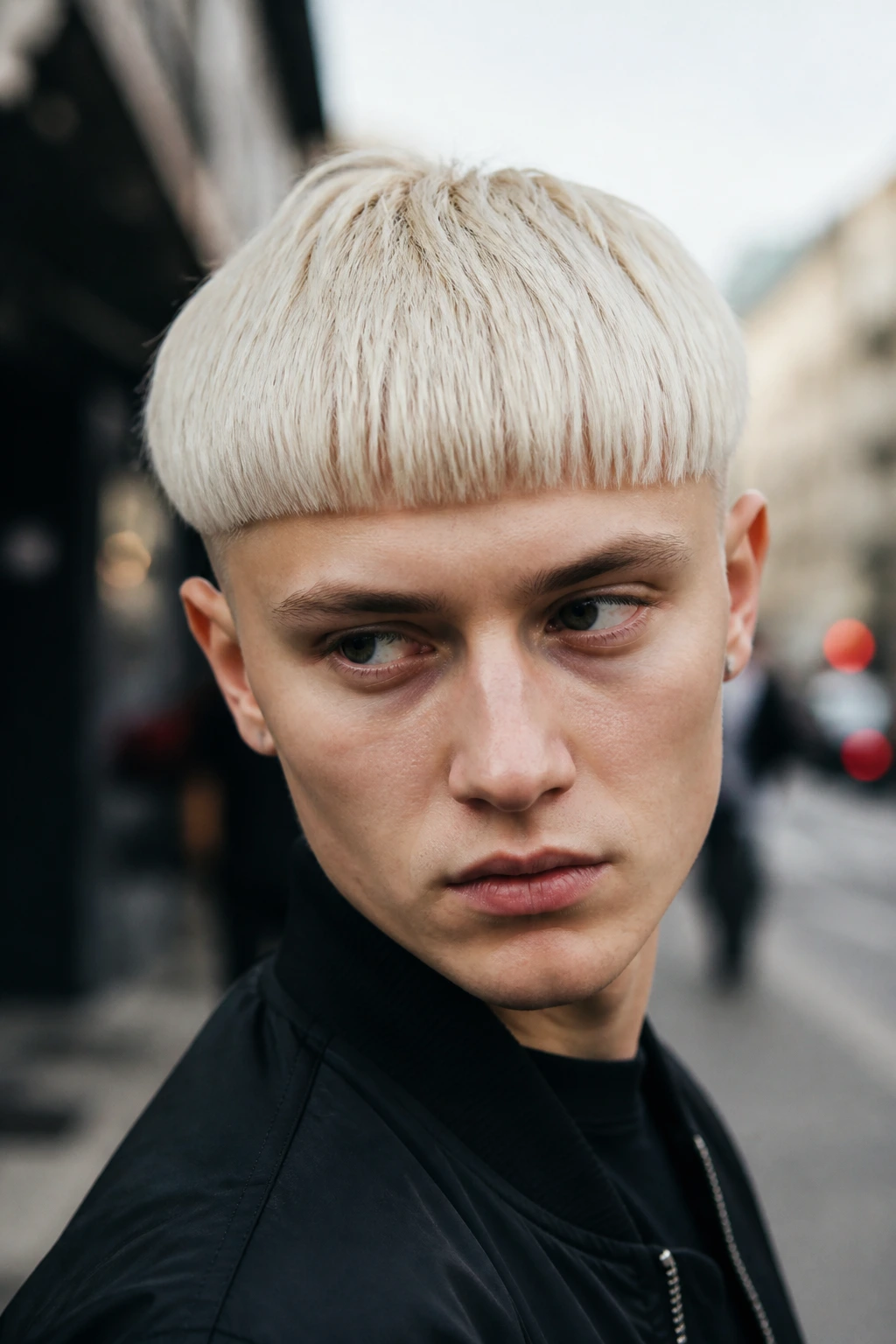 Portrait of man with bleached bowl cut against city backdrop