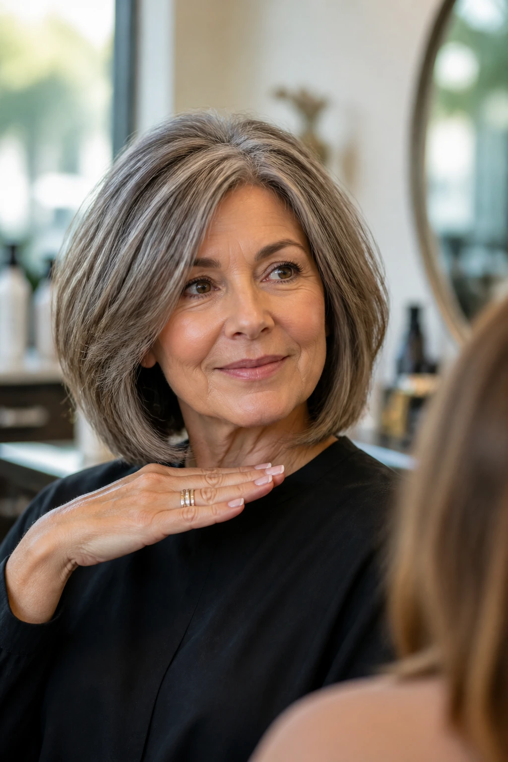 Close-up of an older woman in a salon chair discussing bob length with a stylist; thick glossy hair