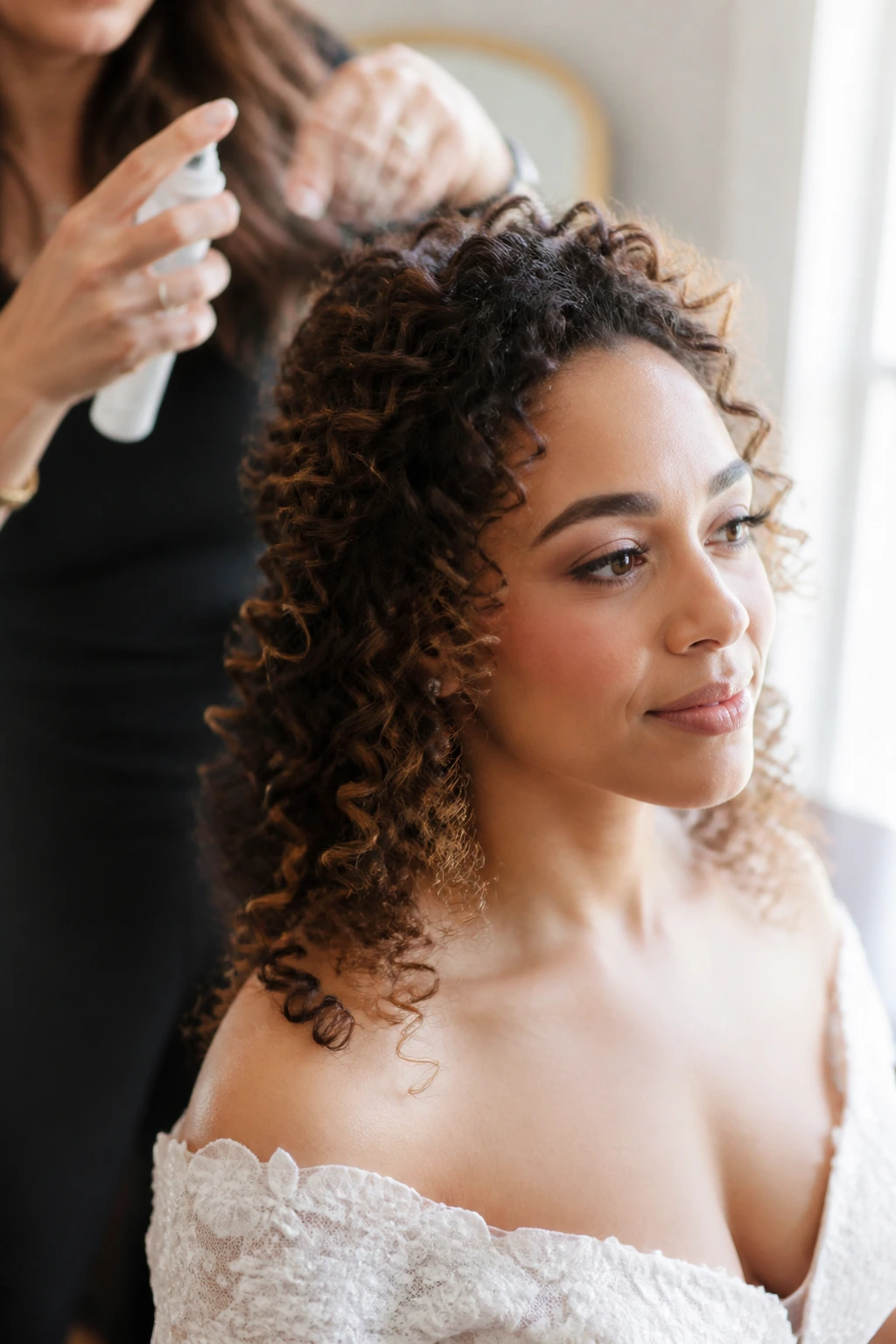 Close-up of a real bride's curly hair being prepped in a bridal suite with warm window light