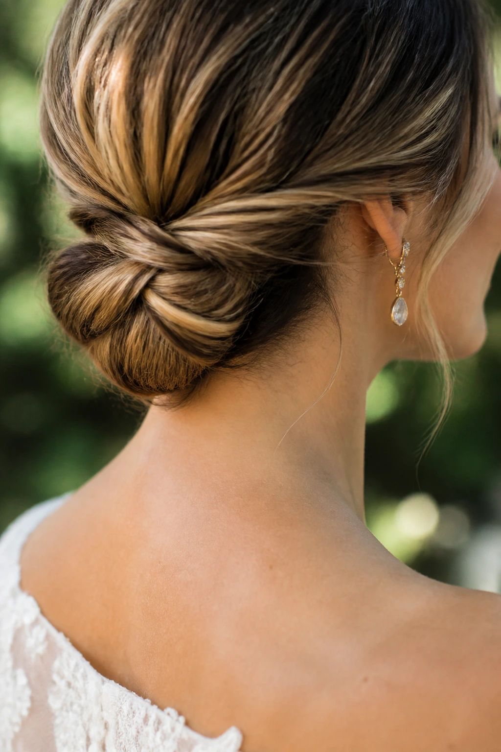 Close-up of bridal low bun at nape in outdoor garden to show summer-heat hairstyle