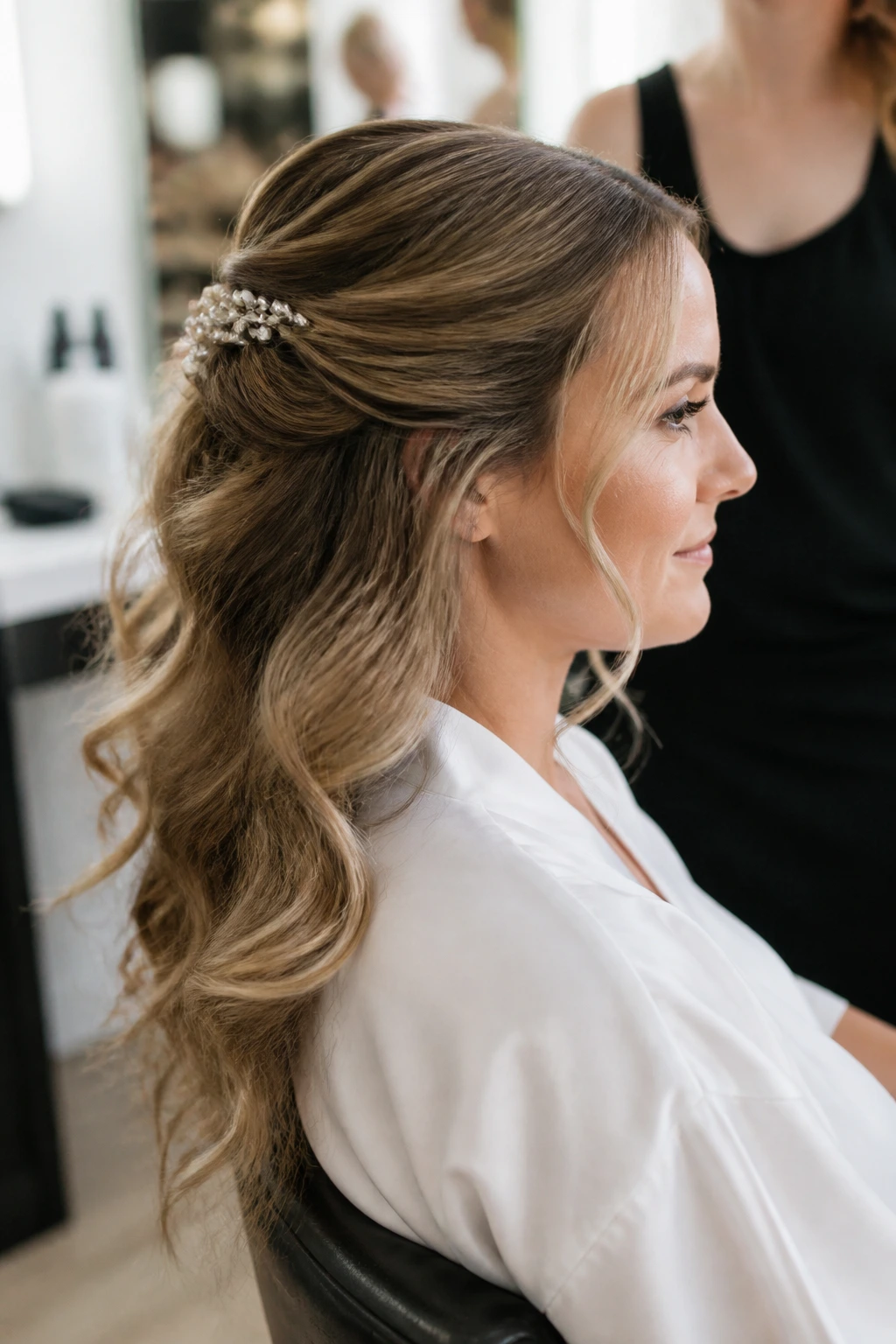Bride in a salon chair with half-up hairstyle and pins, soft lighting
