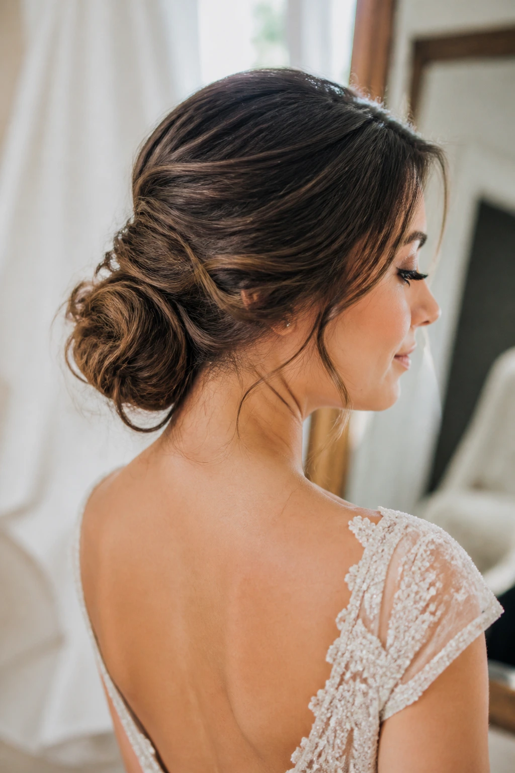 Close-up of a real bride's tousled low nape bun under natural window light