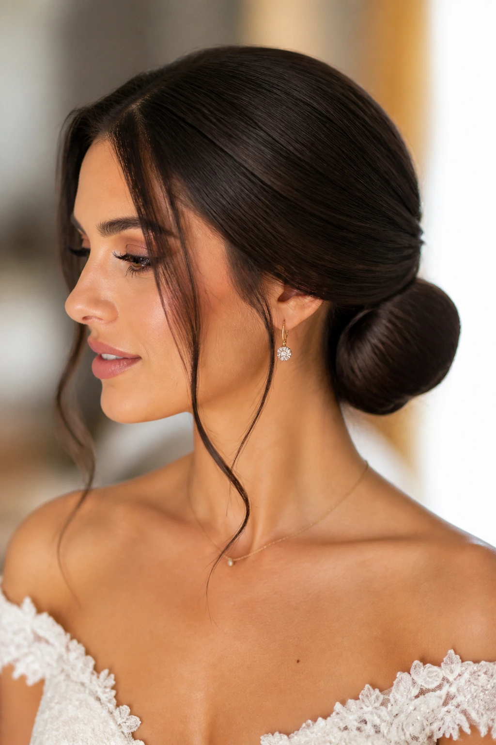 Close-up of a bride wearing a sleek low chignon with face-framing pieces