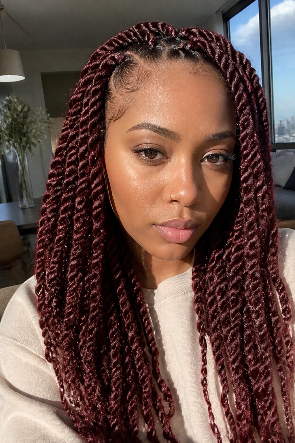 Close-up portrait of a real person with burgundy Havana twists in warm lighting