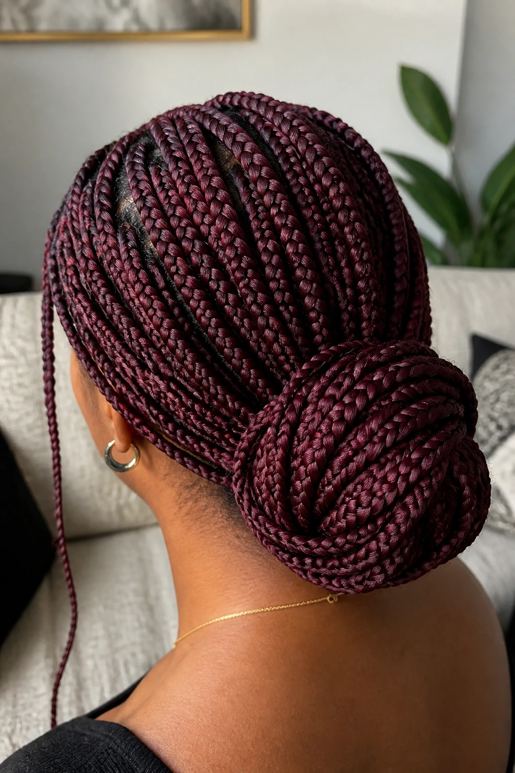 Back of head close-up showing burgundy knotless braids in a low bun