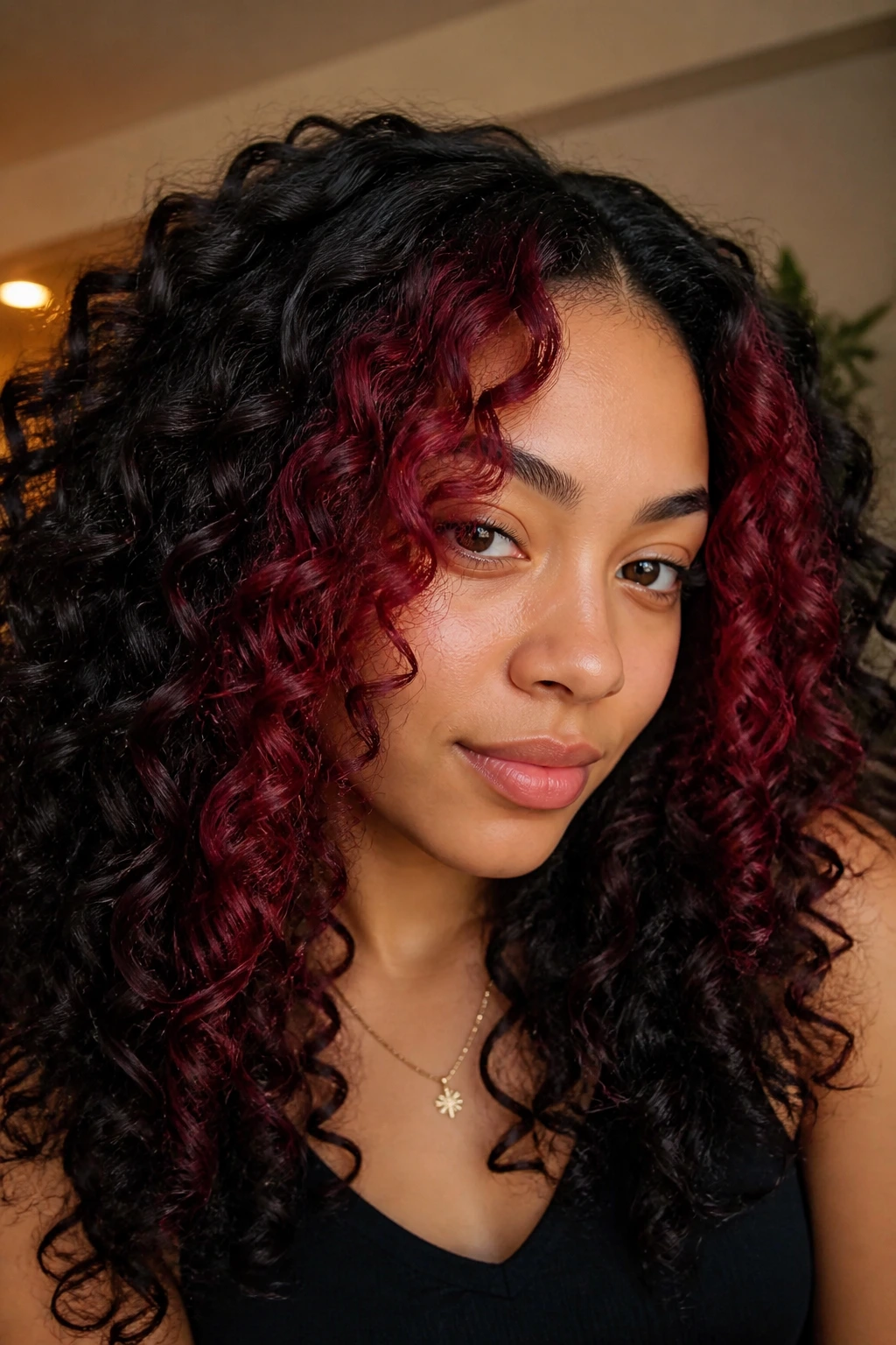 Close-up of burgundy money piece framing the face on curly hair