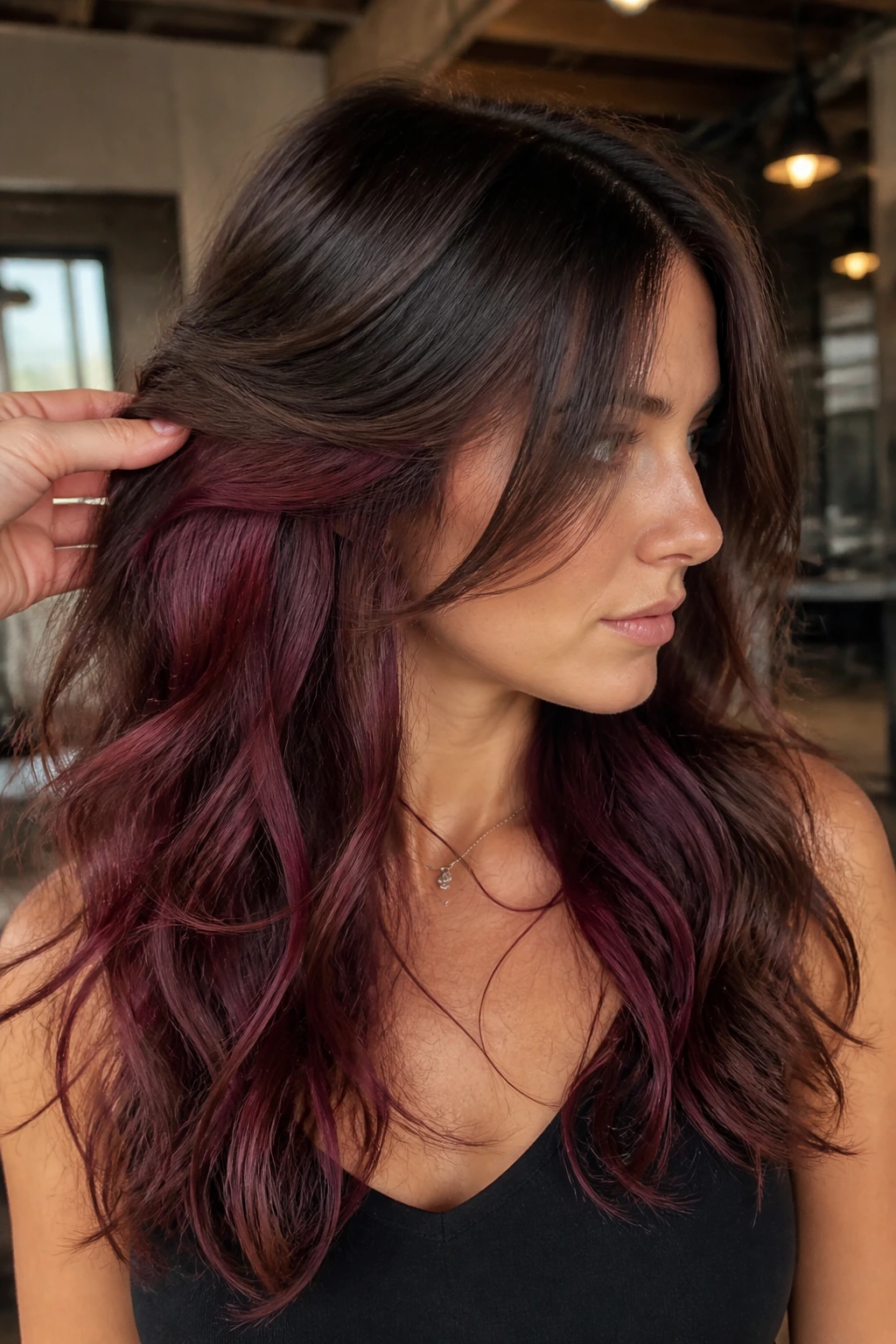 Close-up of a real woman with burgundy peekaboo panels under the crown on wavy hair