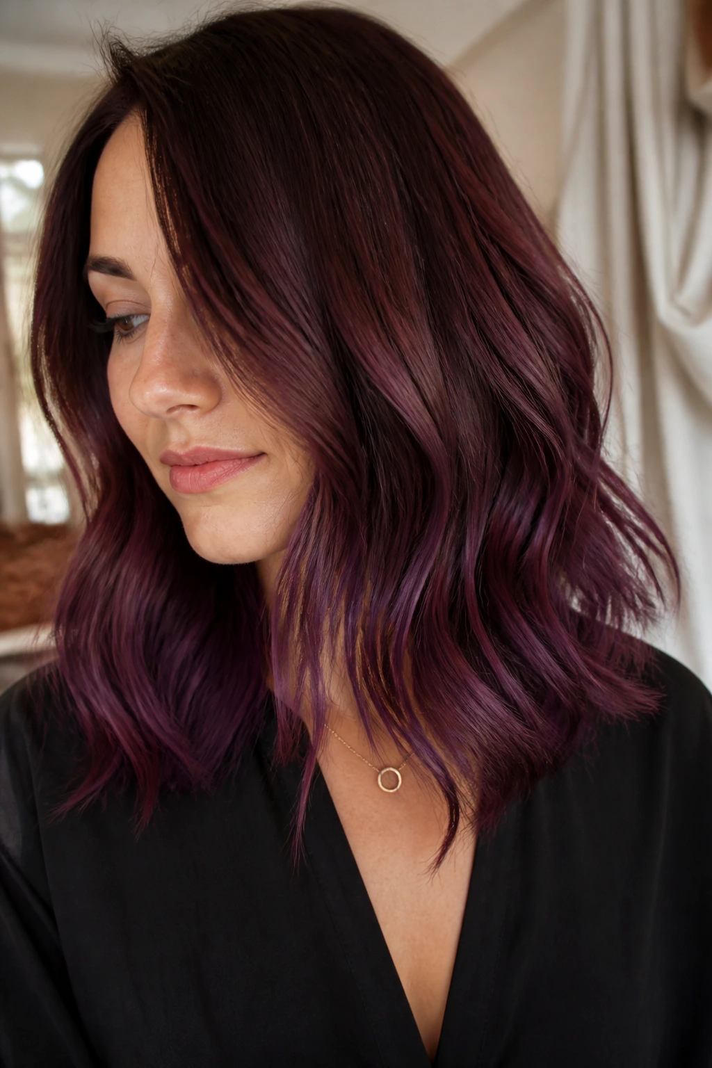 Close-up of a real woman with burgundy to plum ombre on a medium-length hair