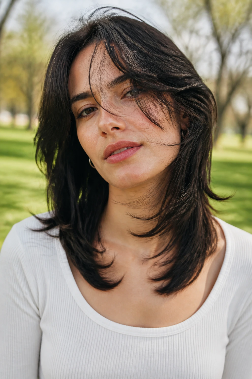 Real woman with butterfly wispy cut at shoulder length in a park.