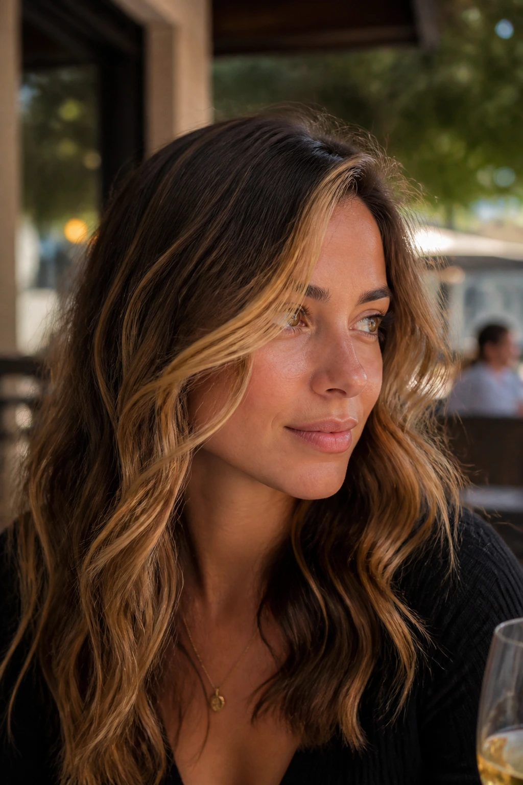 Close-up of a woman with butterscotch money piece swept to the side on wavy hair