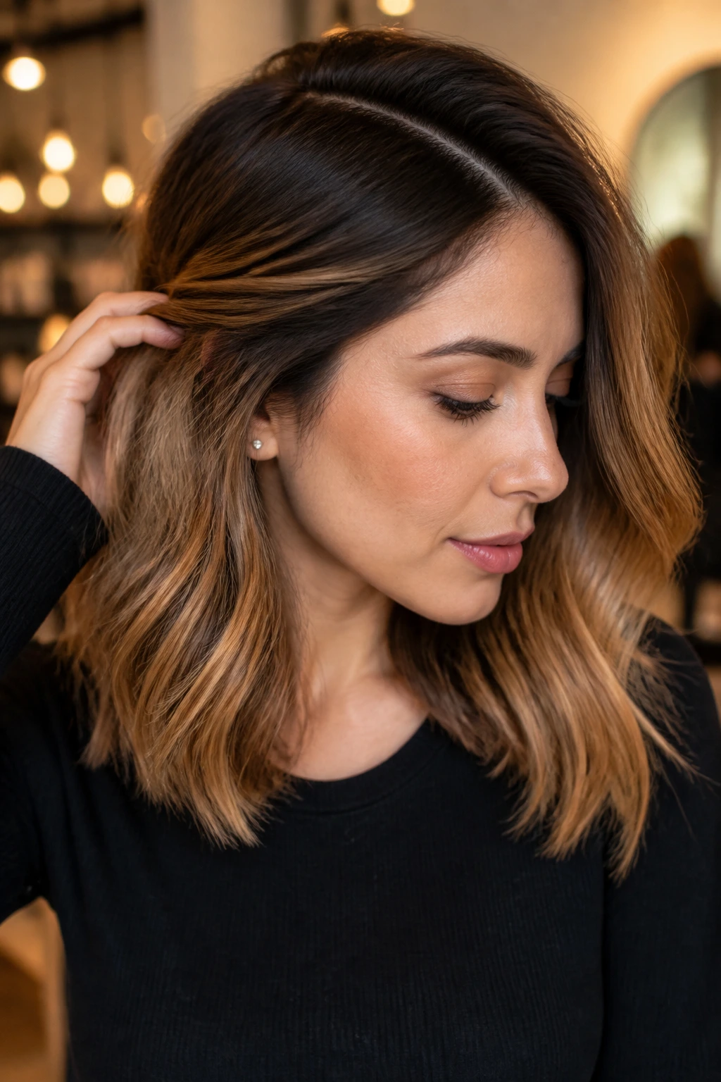 Real woman's shoulder-length hair with caramel melt and shadow root in warm indoor light