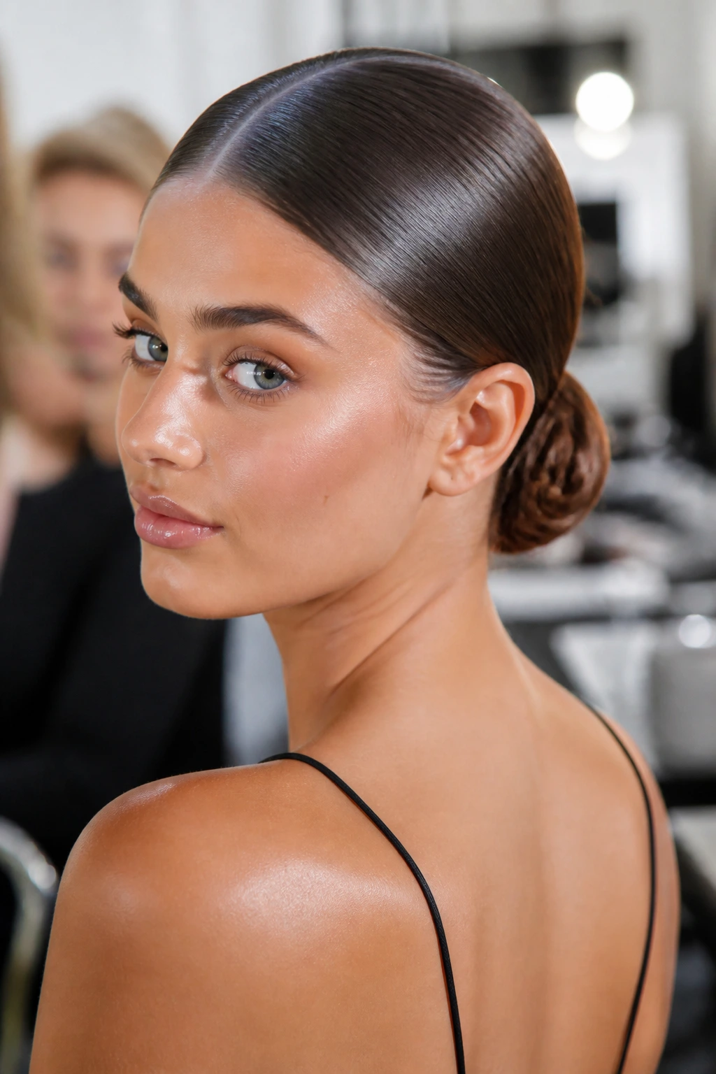 Close-up of a real woman with a center-part and a low bun.
