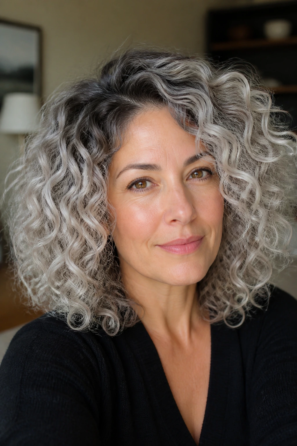 Close-up of real woman with charcoal root shadow on curly hair in a living room
