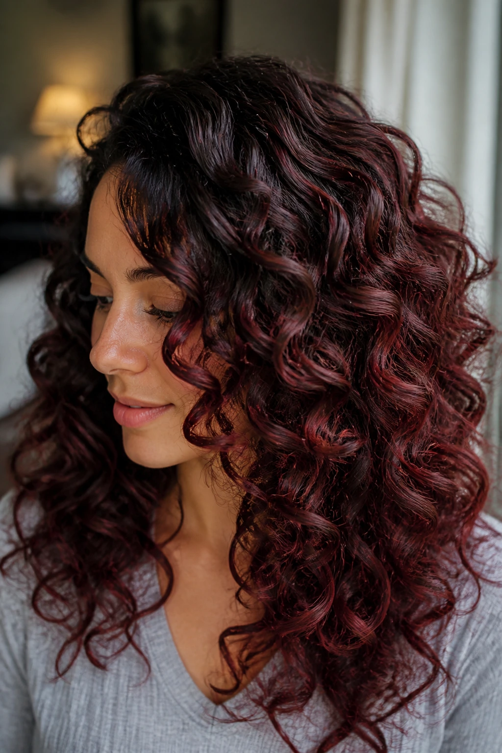 Close-up of curly hair with cherry cola balayage showing red-black sheen