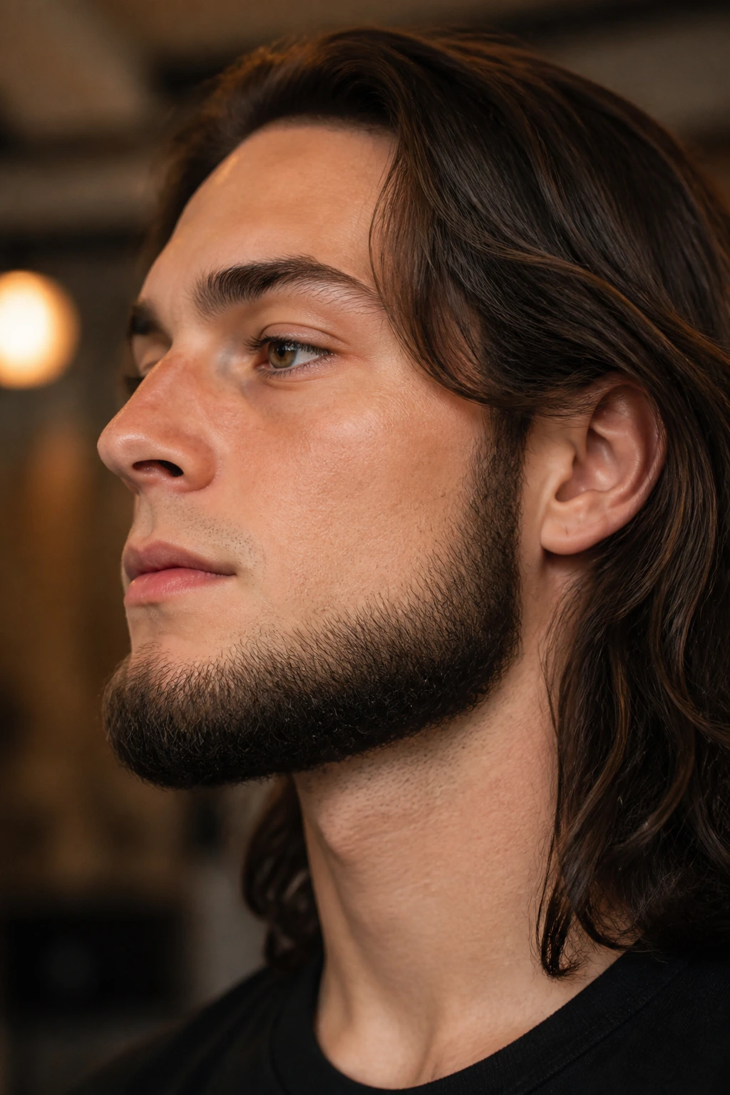 Profile portrait of a man with a chin curtain beard and long hair