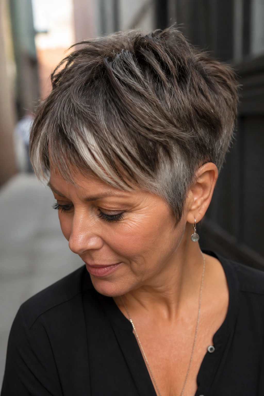Close-up of a real woman with a choppy pixie and silver peekaboo pieces in an urban setting