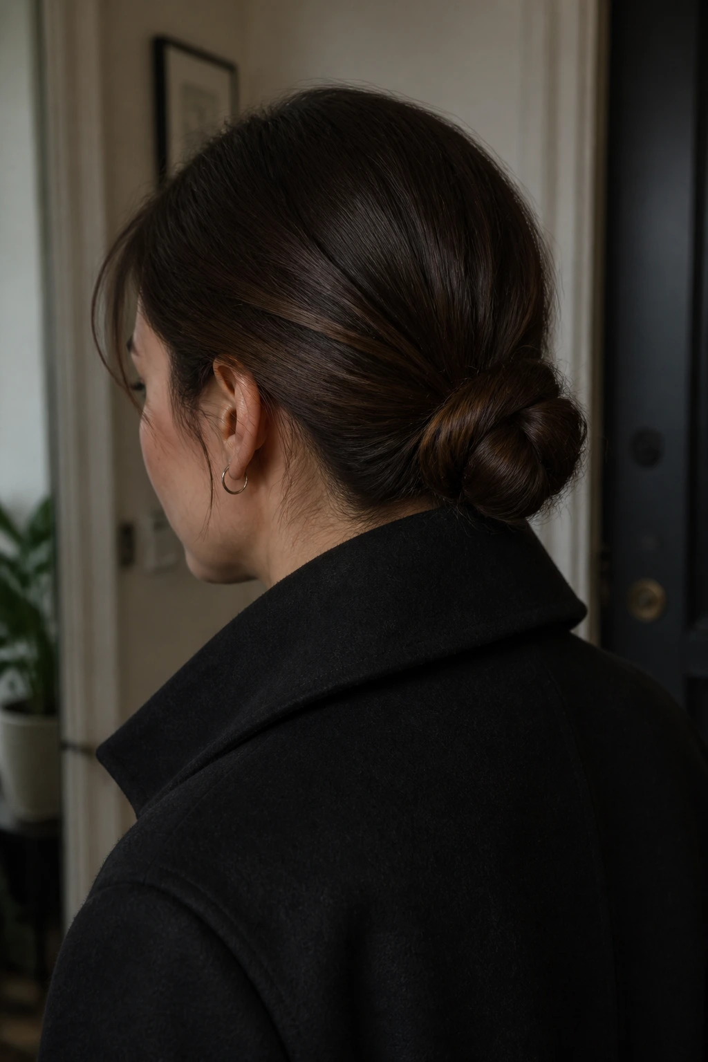 Portrait of a real woman showing a compact coat-collar bun under a jacket collar.