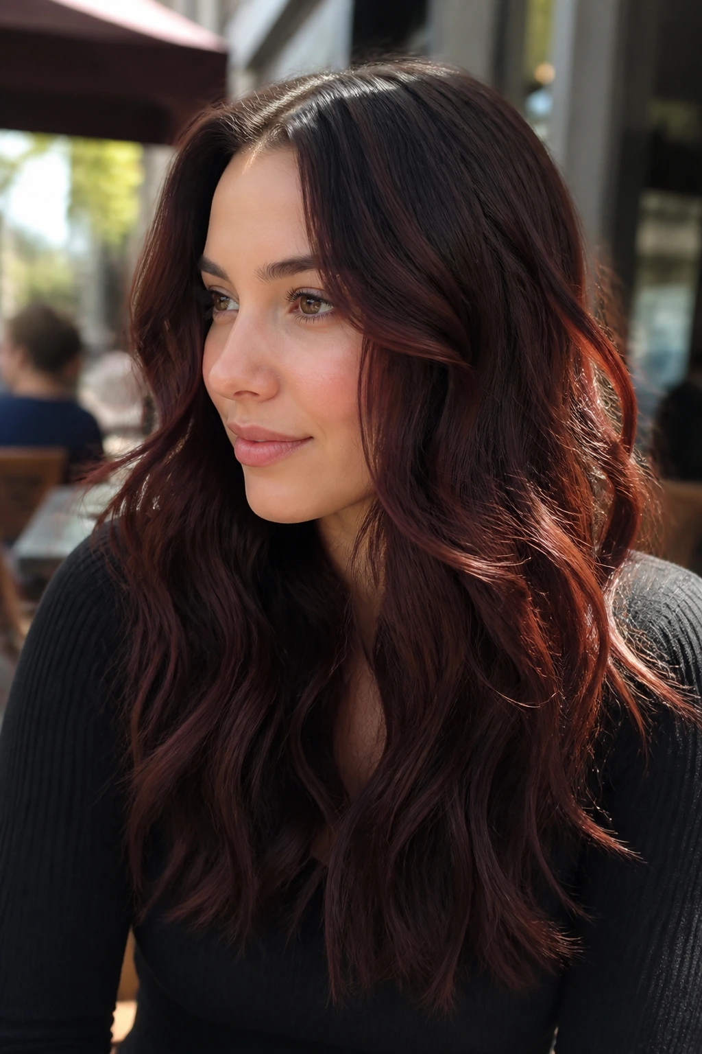 Close-up of a real woman with cocoa cherry cola brunette long waves catching light to show red undertones.