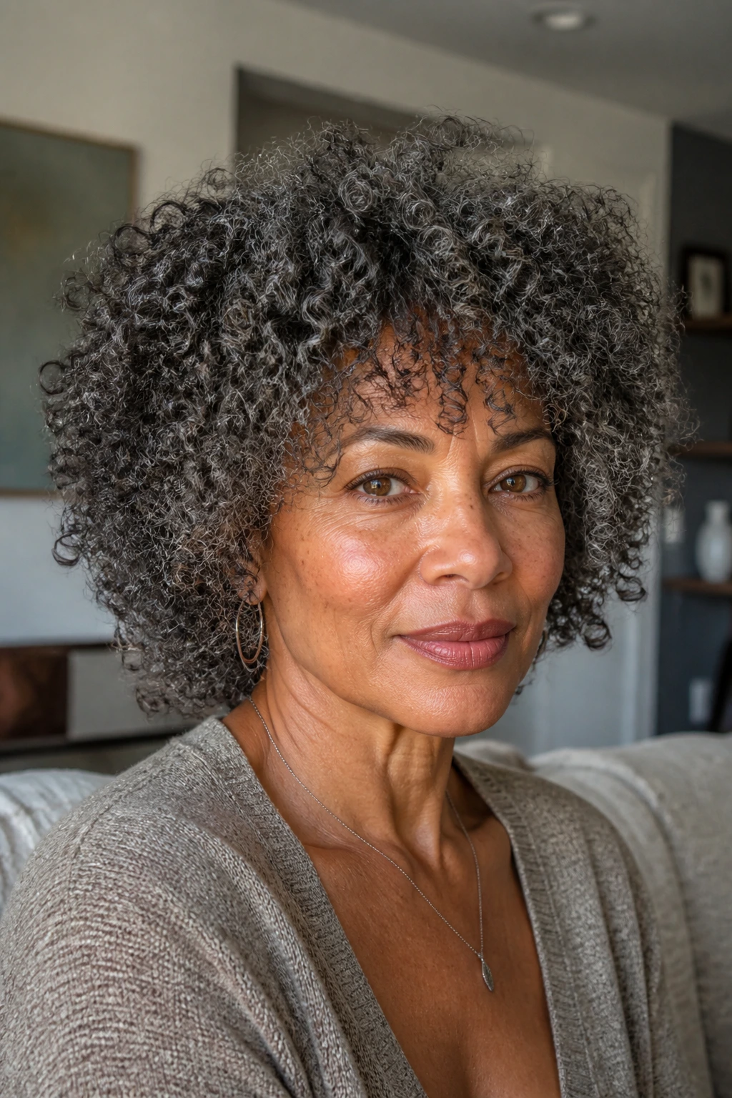 Portrait of a real woman with coily curls and longer top layers forming a rounded silhouette