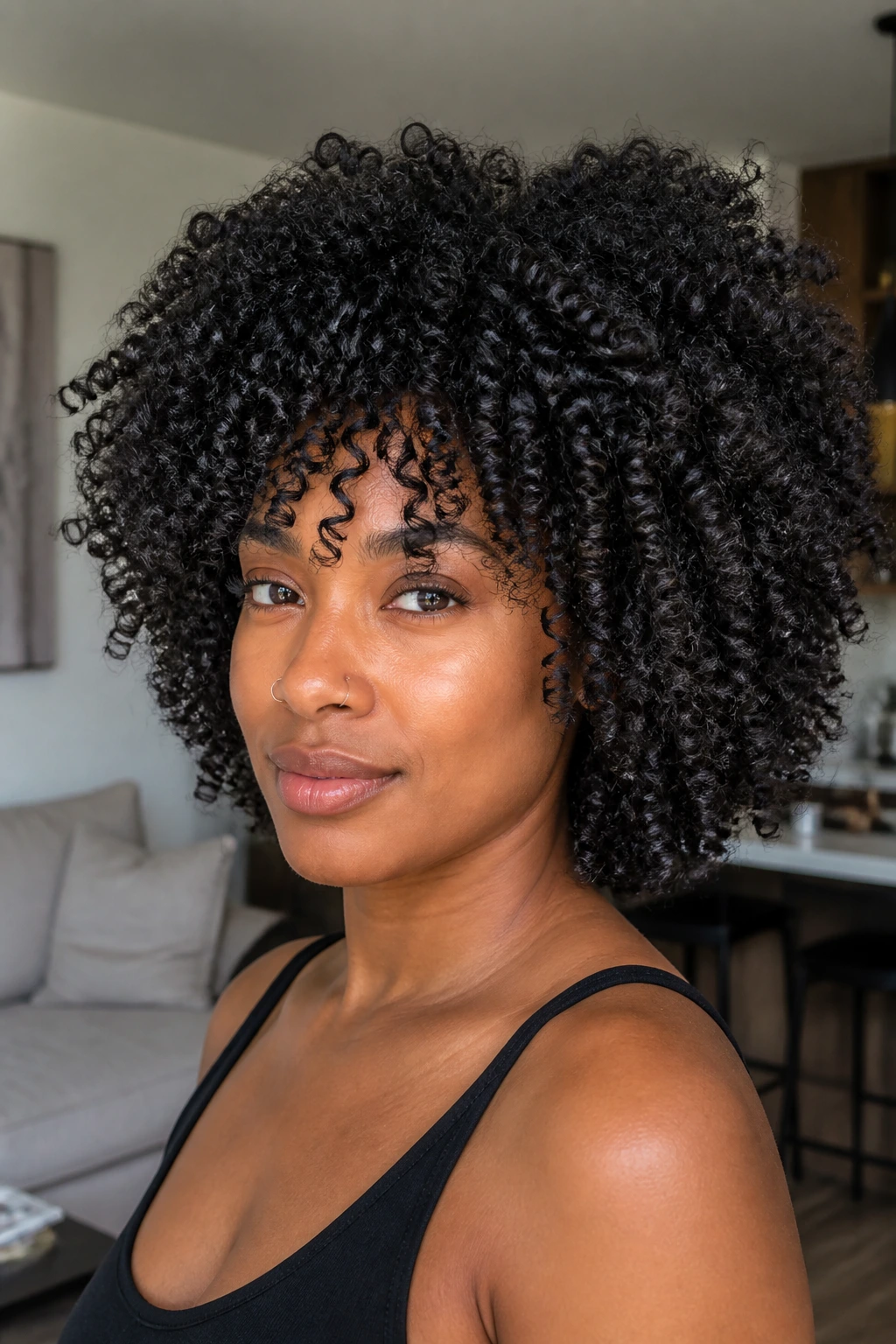Close-up of real woman with coily layered hairstyle in bright living room