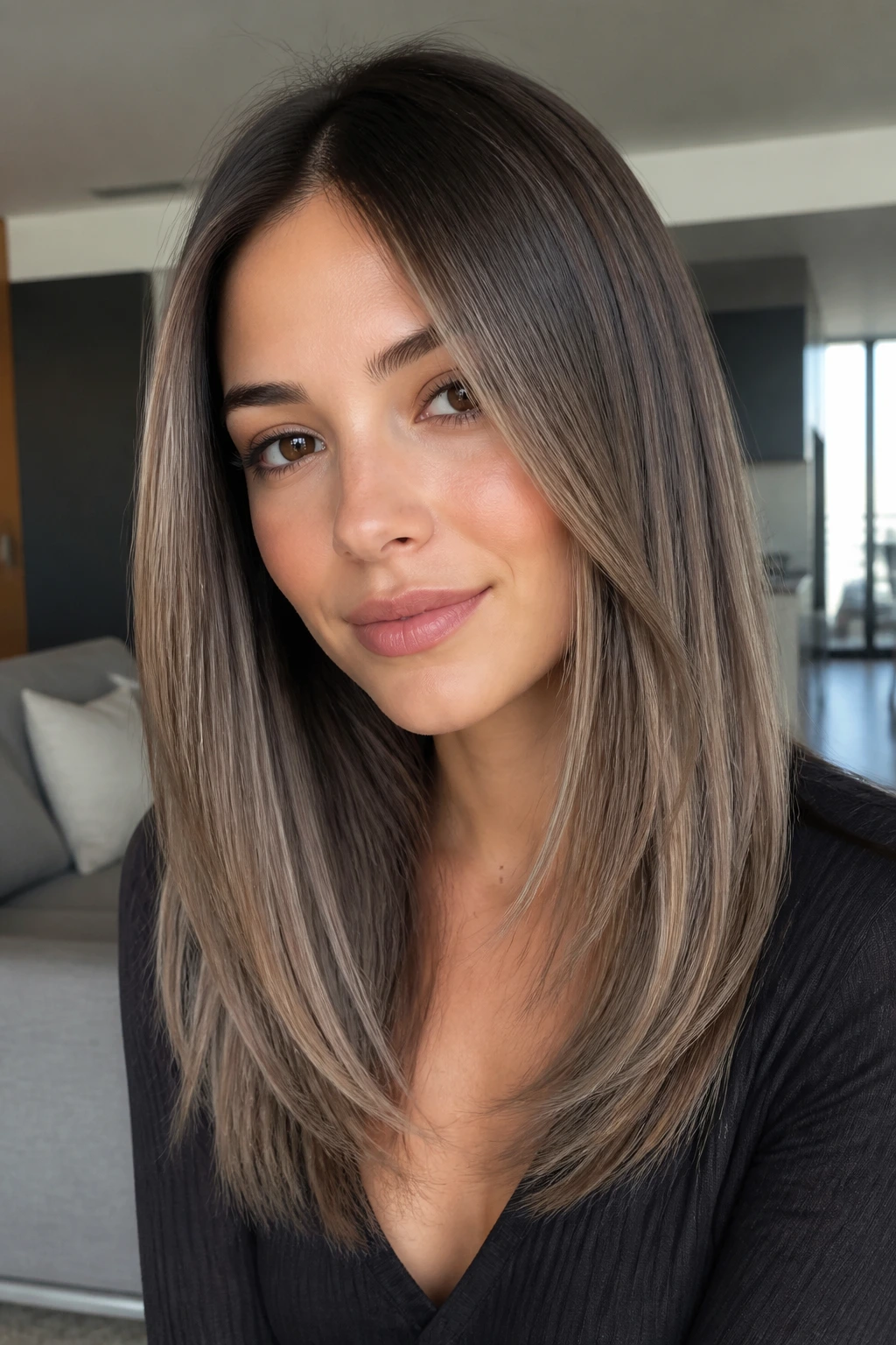 Close-up portrait of a real woman with cool taupe balayage on straight hair.