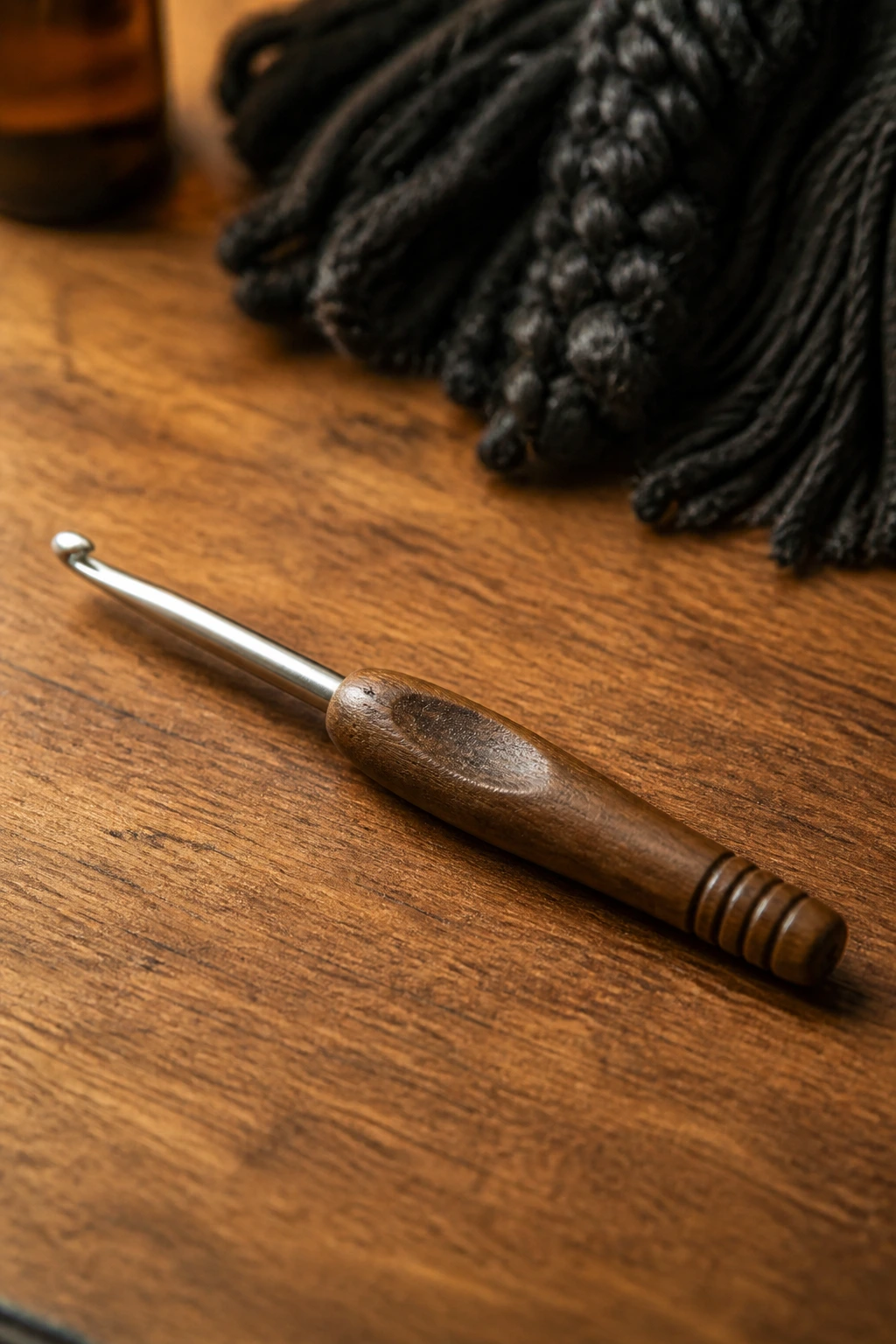 Macro close-up of a crochet hook on a wooden surface.