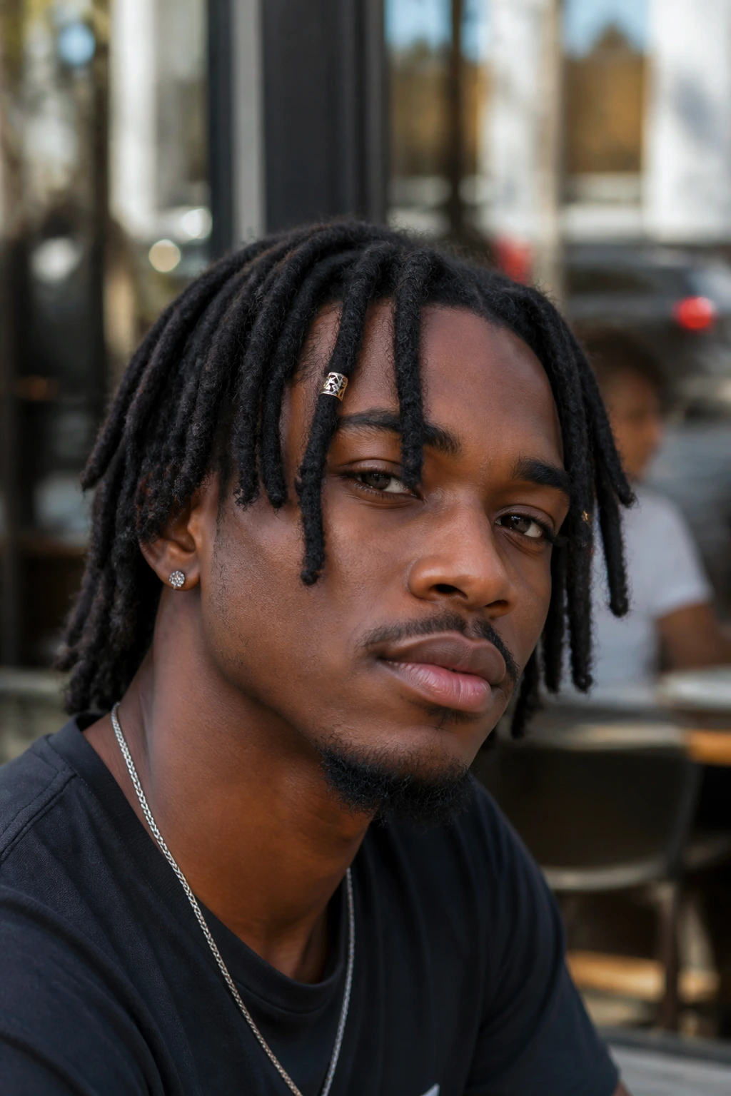 Man with cuffed locs and visible cuffs in front, in soft daylight