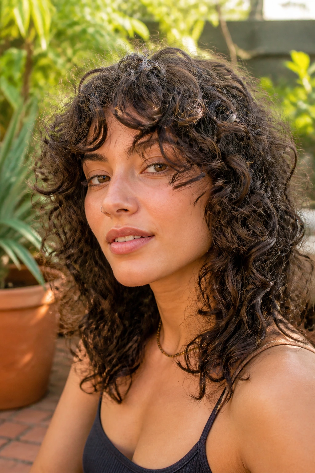 Close-up real person curly curtain fringe wolf cut on sunny garden patio