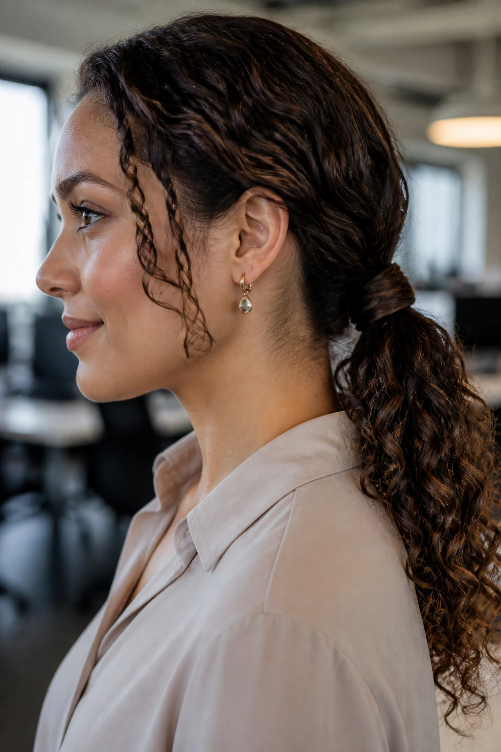 Close-up of a real person with a low curly ponytail featuring a wrapped base in an office