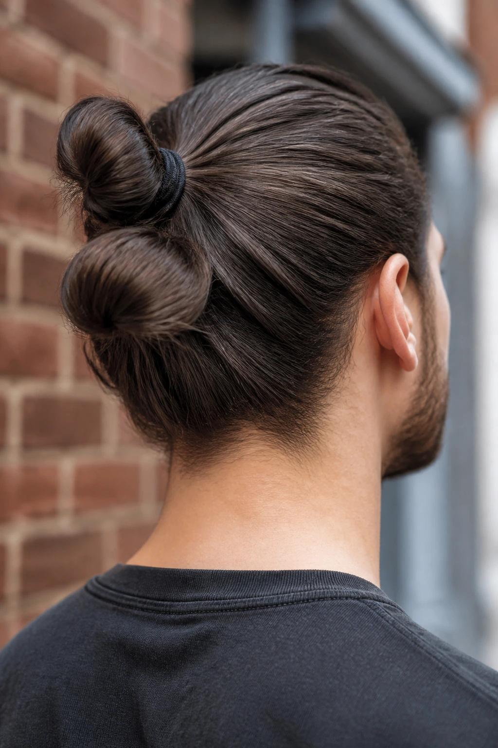 Rear-side close-up of a man with a double bun created by two elastic bands
