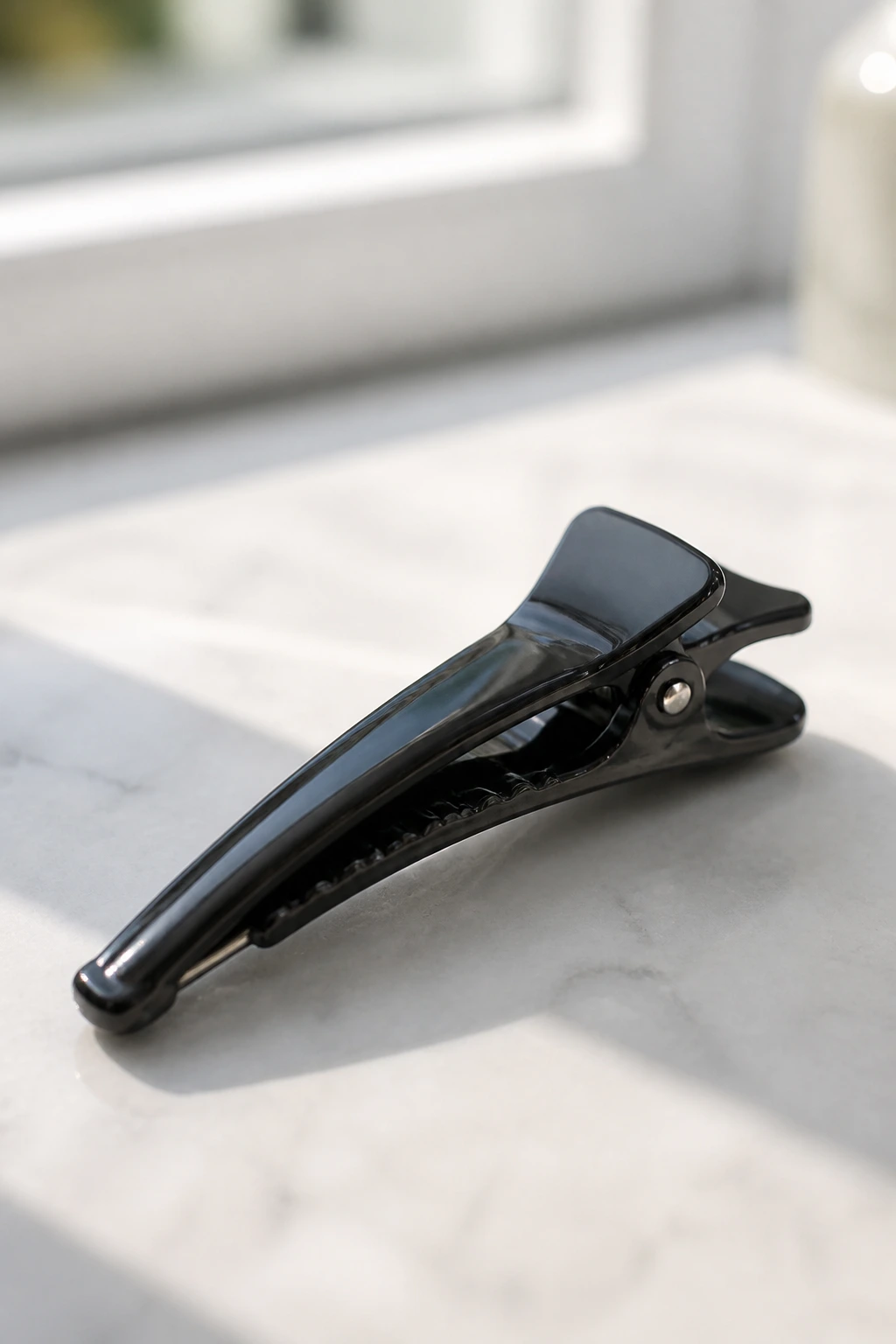 Duckbill clip close-up on pale surface representing essential styling tools