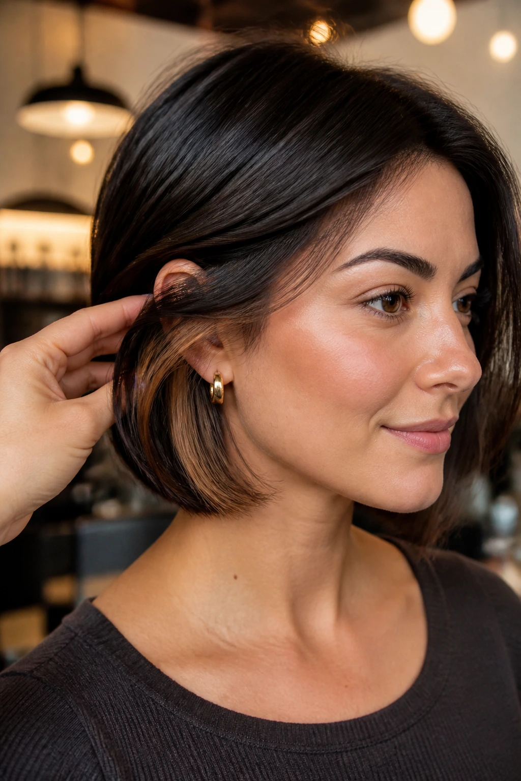Close-up of espresso hair with caramel peekaboo underlayers in a chic salon