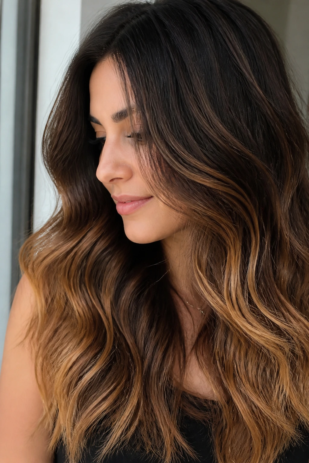 Close-up of a real woman with espresso-to-toffee gradient on dark wavy hair under window light