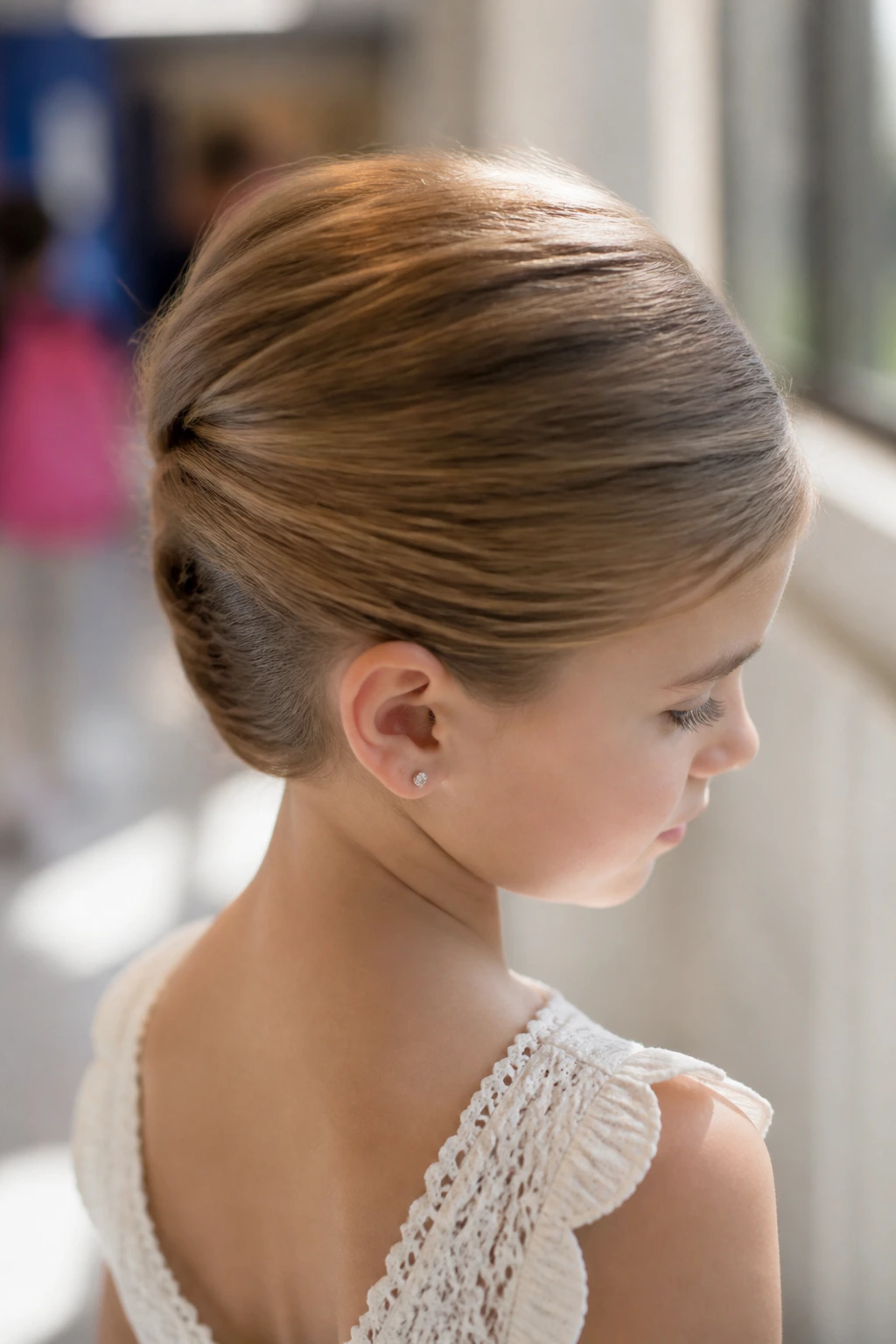 Close-up of a child with a small French twist tucked roll in natural light