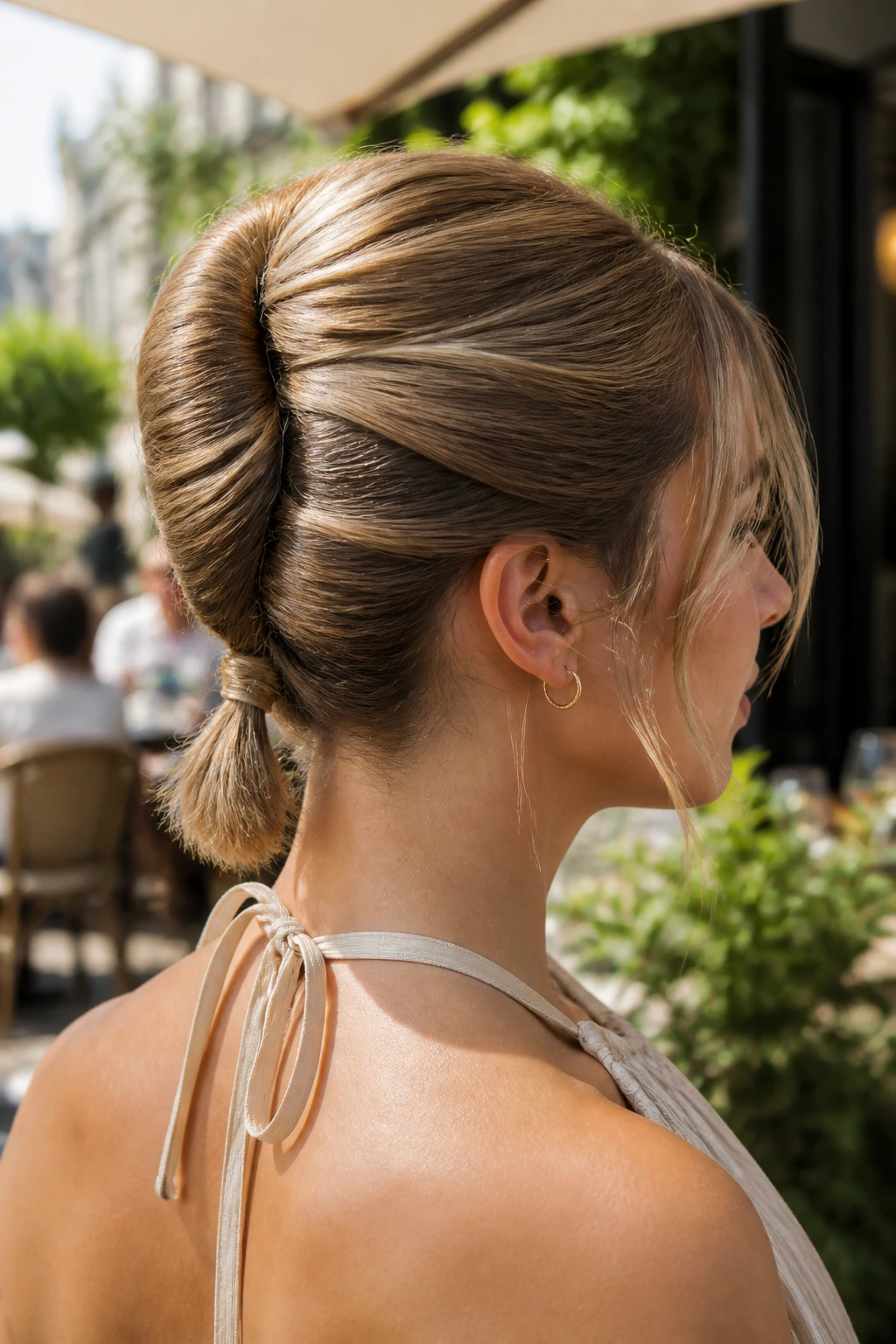 Close-up portrait of a woman with a pony-roll French twist in sunlit cafe