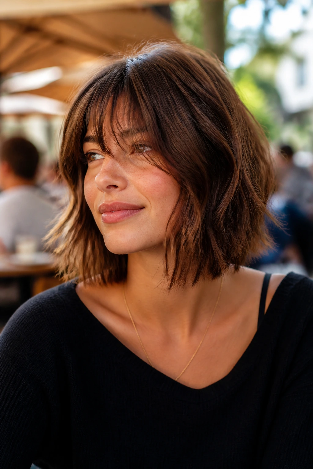 Real person with layered bob and soft fringe in outdoor cafe lighting
