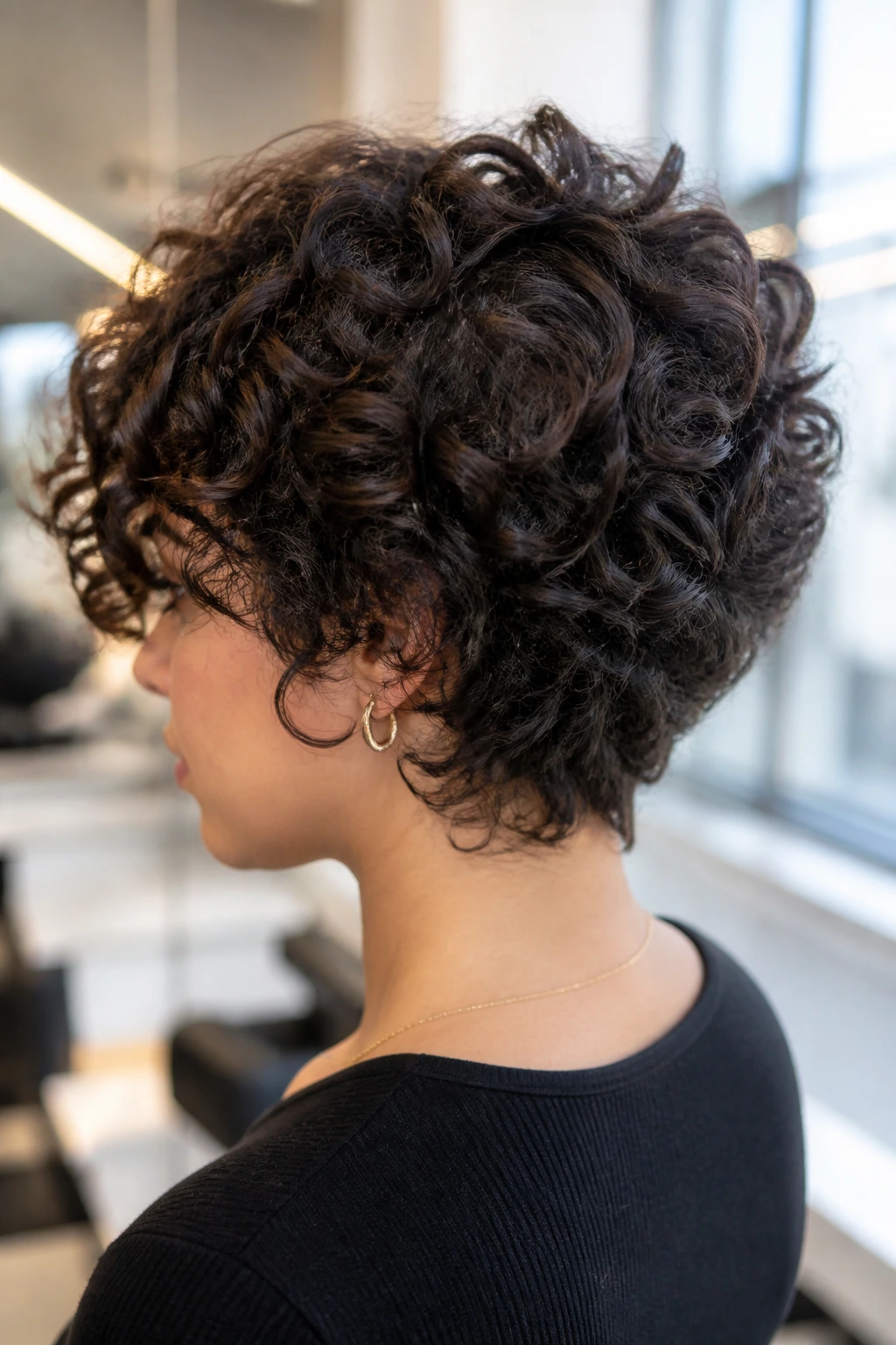 Close-up of a real person with graduated layers in a thick curly haircut, back and crown visible