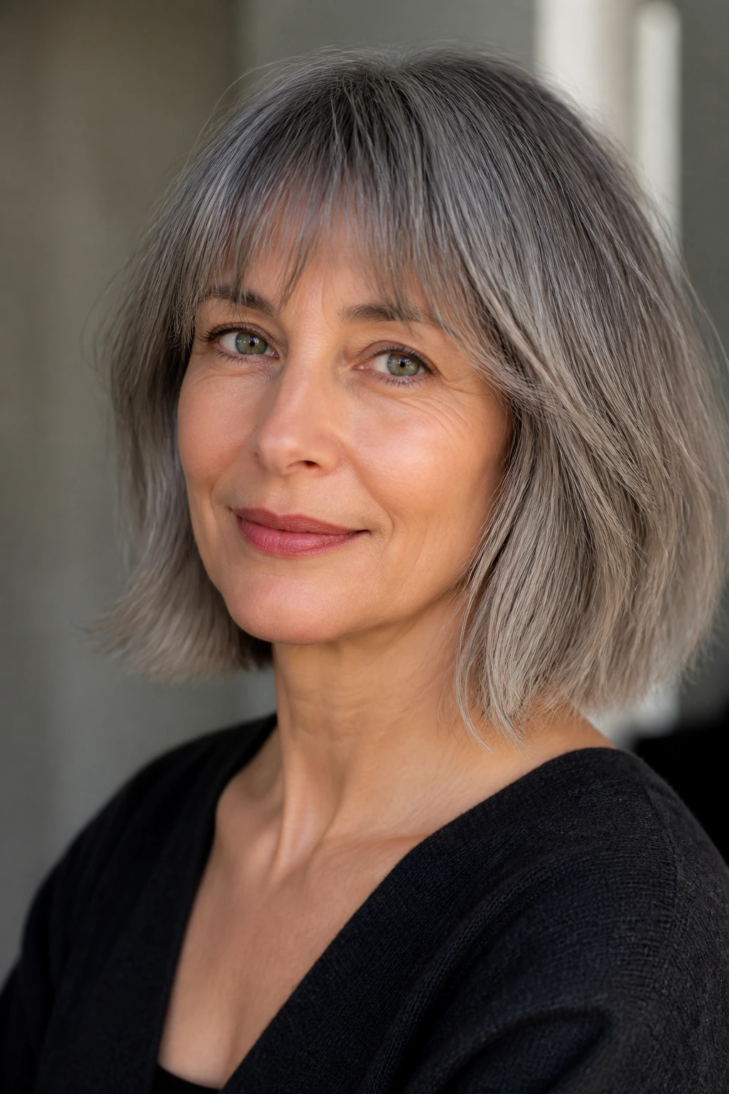 Real woman with a gray lob and soft fringe, close-up portrait.
