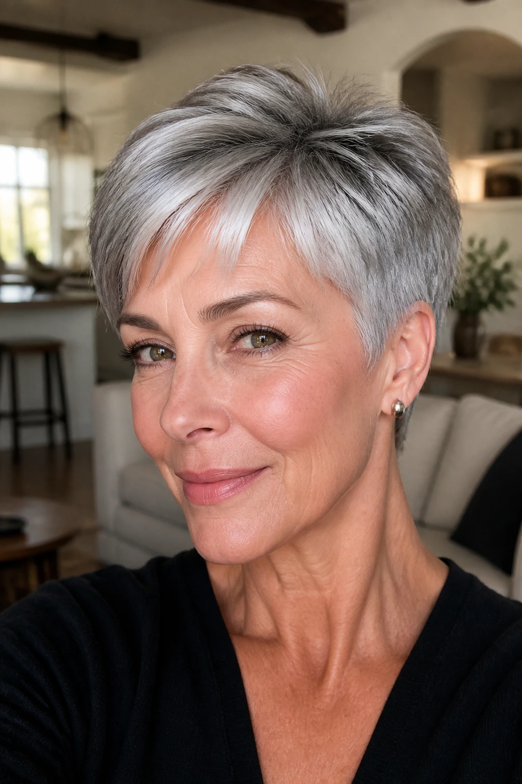 Close-up of a real woman's short gray pixie with glossy finish and lifted crown in a warm living room setting