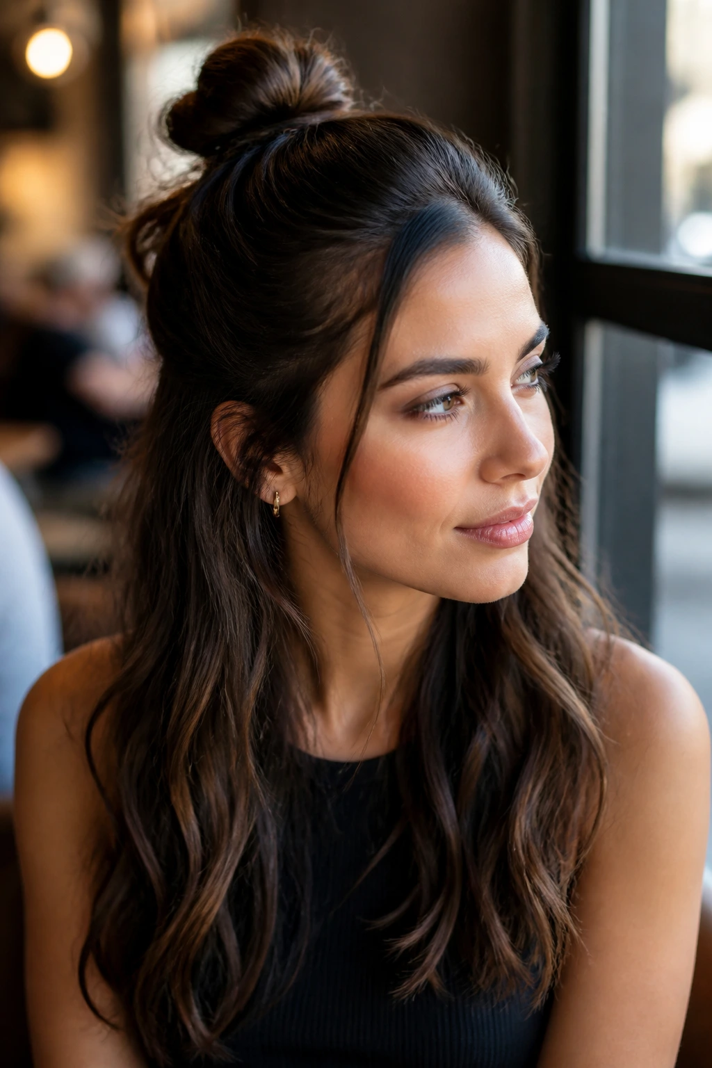 Close-up portrait of a real woman with a half-up mini bun and loose lower hair.