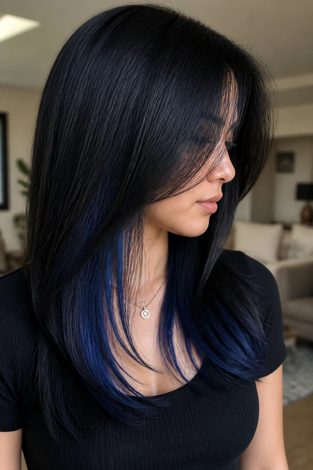 Close-up of a real woman with hidden sapphire underlayer in straight black hair under soft light