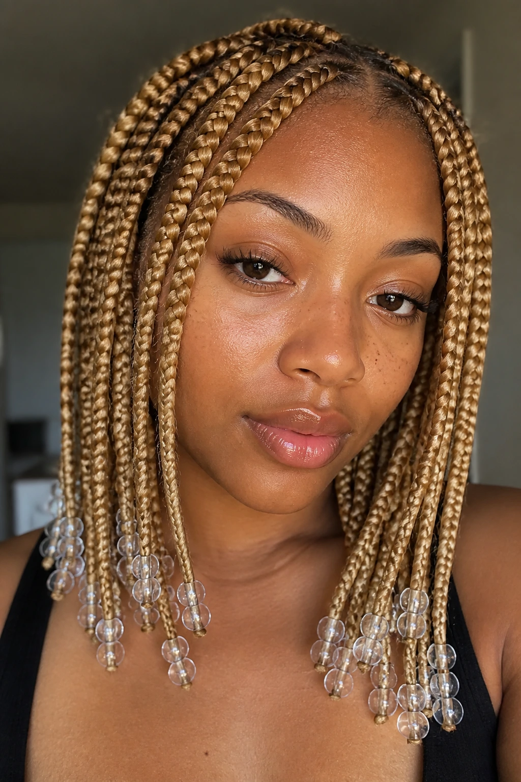 Portrait of a woman with honey-blonde knotless box braids and clear beads at the ends